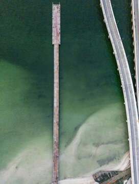 Aerial view of the long pier at Puerto Progreso extending into the turquoise waters of the Gulf of Mexico, with the adjacent coastal highway in Progreso, Yucatan, Mexico.