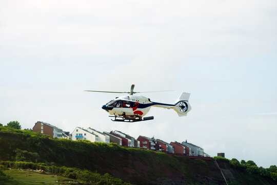 Emergency Medical Service Helicopter Flying Over Coastal Town Hillside Buildings, Concept Of Air Transportation