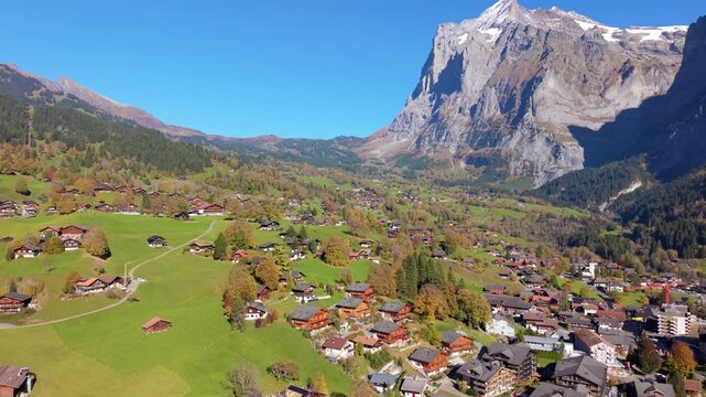 Aerial autumn view of Grindelwald alpine village with traditional chalets on green hills. Grindelwald, Canton of Bern, Switzerland.