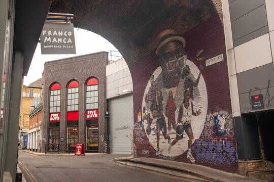 LONDON - Atlantic Road Brixton &ndash; Five Guys and large basketball mural under the railway arch.