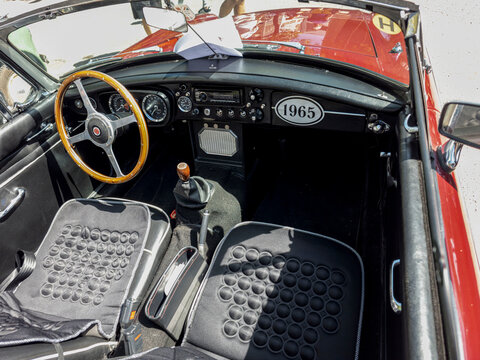 TAVERNES BLANQUES, SPAIN - JUNE 14, 2026.High angle view into classic red MG MGB convertible cabin with wooden steering wheel and vintage dashboard