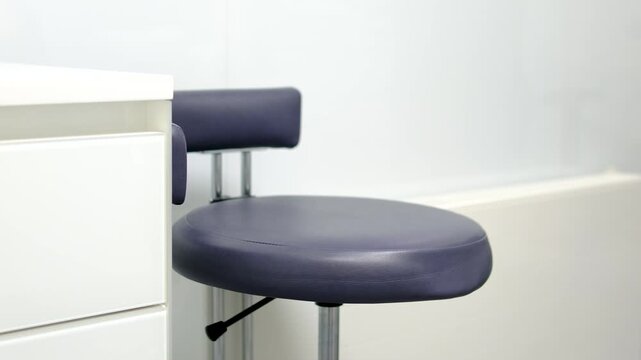 Dental assistant stool beside treatment workstation in modern dentistry clinic clean professional interior