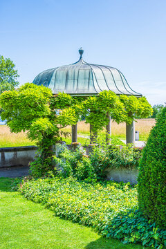 Garden scene with green bushes and flowers in a well-maintained landscape surrounded by a stone wall on a sunny day