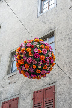 Spherical floral decorations hang in a pedestrian zone in Germany during a sunny day near old buildings and shops