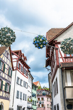 Spherical floral decorations hang in a pedestrian zone in Germany during a sunny day near old buildings and shops