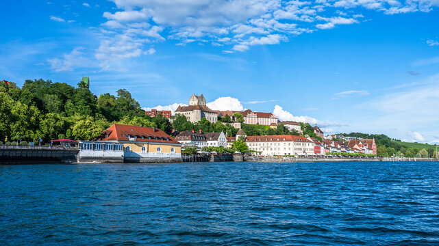 View from the water showing the town of Meersburg on Lake Constance with buildings on the hillside under a blue sky