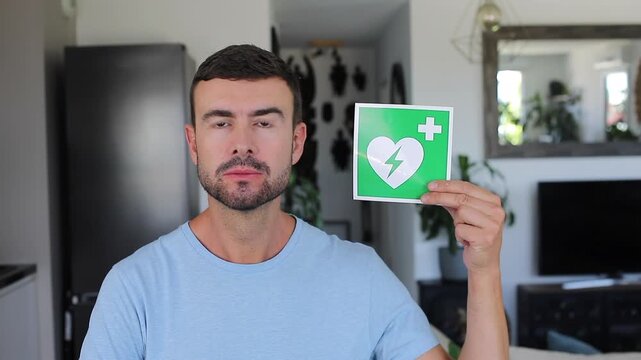 Man holding green and white AED sign showing medical emergency heart symbol
