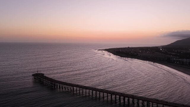 Ventura Pier and Beach coastline stretching into the distance during sunset after dusk. The expansive frame captures the full length of the pier, beach and ocean in warm evening light.