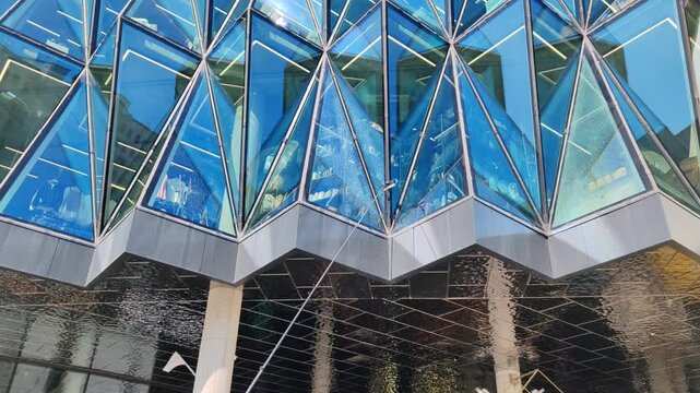 telescopic brush cleans building facade with water spray. professional cleaning equipment removes dirt from glass or metal panels. modern facade maintenance ensures clean appearance for buildings.