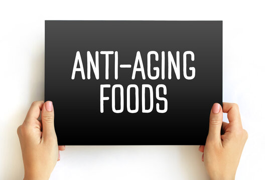 ANTI-AGING FOODS sign held by person. Focus on superfoods, antioxidants, longevity diet, and nutritional habits to slow down aging process and maintain youthful energy and skin health.