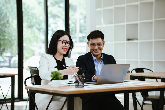 Two business professionals collaborating on a laptop in a modern office, discussing ideas and reviewing projects, showcasing teamwork, productivity, and workplace communication.