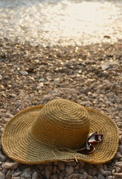 Women's woven summer hat and glass on the beach summer fashion accessory background