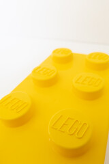 Naklejka premium Bradford, UK June 24 2026 - Close-up of a yellow LEGO storage container lid designed to resemble an ordinary LEGO brick, isolated on a white background with copy space.