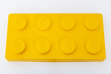 Naklejka premium Bradford, UK June 24 2026 - Close-up of a yellow LEGO storage container lid designed to resemble an ordinary LEGO brick, isolated on a white background with copy space.