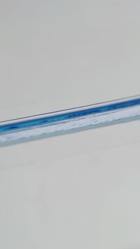 Vertical video: Touching white sheet, fine tip brush pulling blue gel forming streak, copy space