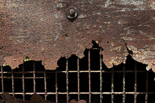 Close-up of heavily rusted metal sheet and corroded wire mesh, revealing peeling layers, weathered textures and industrial decay in an abandoned structure