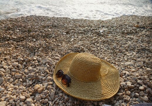 Women's woven summer hat and glass on the beach summer fashion accessory background