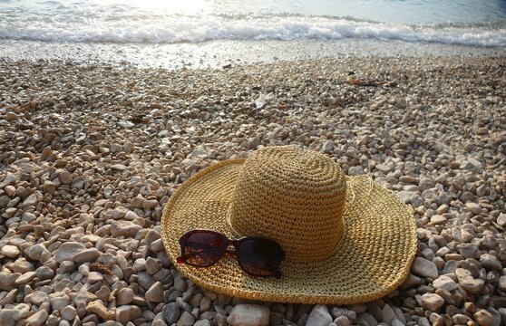 Women's woven summer hat and glass on the beach summer fashion accessory background
