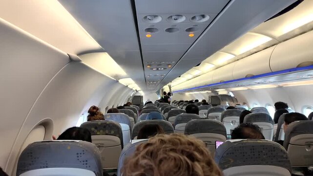 Static shot of an airplane cabin interior with condensation mist from vents while passengers wait during boarding