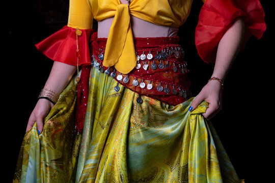 Gypsy dancer holding colourful costume with coin scarf close up on dark background