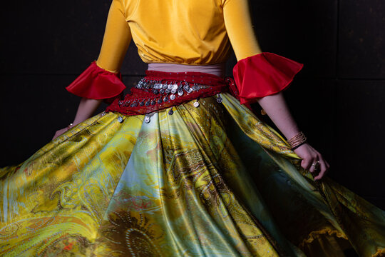 Gypsy dancer holding colourful costume with coin scarf close up on dark background