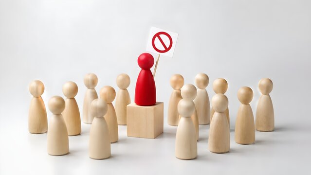 Red wooden figure holding prohibition sign standing on block above crowd representing protest or rejection