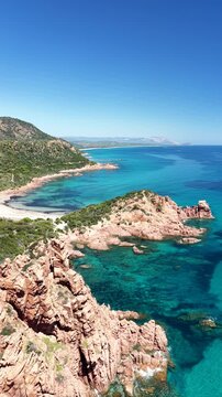 4K drone flight along the Marina di Gairo coastline, featuring Su Sirboni Beach and Cala Laus. Turquoise waters, striking red rocks, and the unspoiled beauty of Sardinia, Italy