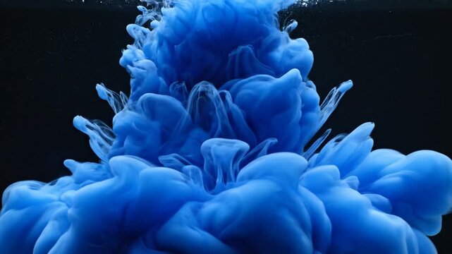 Deep blue ink cloud exploding in black water.