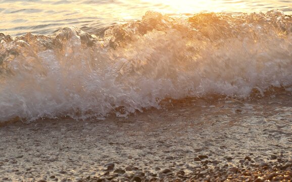 Golden wave sea splash on the beach in beautiful sunset with sparkle and shine,summer sea water splash background