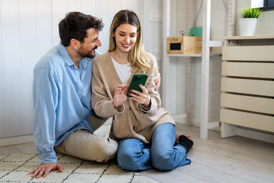 Smiling couple embracing while looking at smartphone. People sharing social media on cellphone.