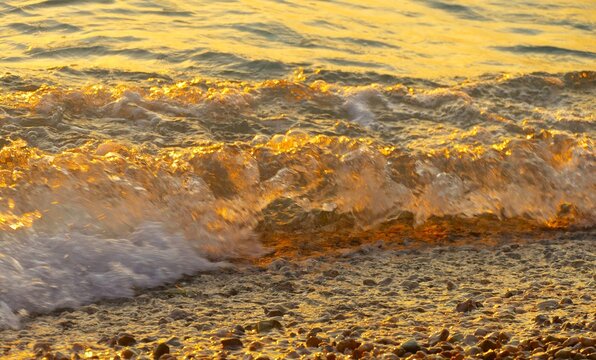 Golden wave sea splash on the beach in beautiful sunset with sparkle and shine,summer sea water splash background