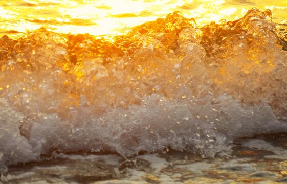 Golden wave sea splash on the beach in beautiful sunset with sparkle and shine,summer sea water splash background