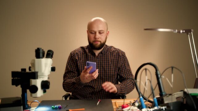 Technician Inspecting Smartphone at Electronics Workbench