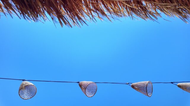 Handmade lanterns and straw wicker swaying in wind create charming atmosphere. Perfect for cozy, decorative and outdoor themes, copy space, slow motion