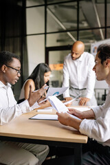 Fototapeta premium A diverse team collaborates, reviewing financial metrics and signing contracts at a table, showcasing teamwork and decision-making in a professional environment.