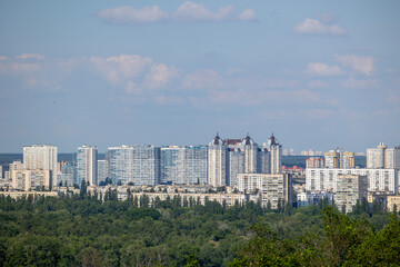 Fototapeta premium Kyiv, Ukraine, offers a panoramic view of the left bank's vibrant residential areas across the majestic Dnipro River, showcasing modern high-rise apartments amidst lush urban greenery and expansive ci
