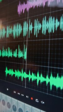 Vertical shot of digital audio computer workstation screen showing green and purple sound waveforms playing. Footage is suitable for projects on podcasting, music production, and sound design