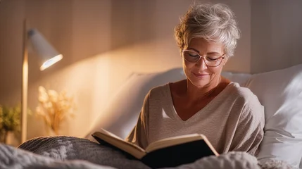 Senior Woman Reading Book in Bed as Relaxing Evening Routine © sema_srinouljan