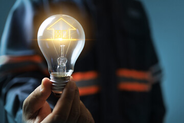 Obraz premium energy saves concept with engineer holding light bulb as filament house icon represents encourage people to electricity save