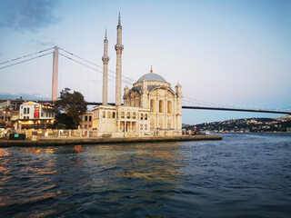 Obraz premium Istanbul turkey ortakoy mosque on bosphorus with bridge and water under clear blue sky. Scene represents travel, architecture, religion, and iconic city landmark concept.