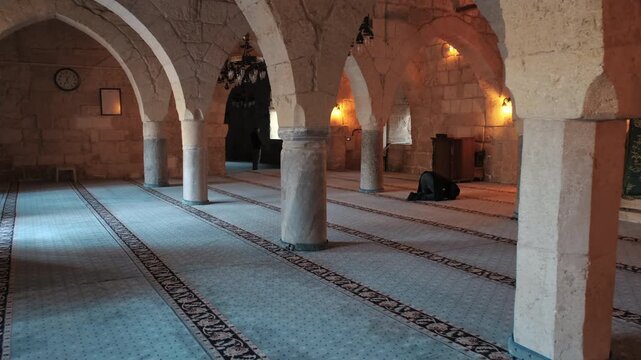 Muslim Man Praying Inside the Stone-Arched Interior of the Historical Yag Mosque in Adana, Turkey