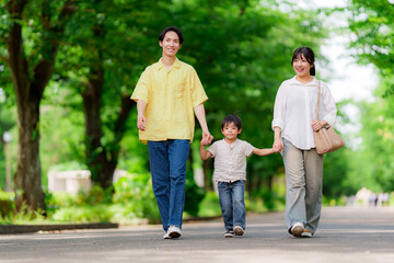 Fototapeta premium 手を繋いで公園を歩く三人家族