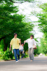 Obraz premium 手を繋いで公園を歩く三人家族