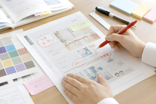 Printed flyer proofing with red correction marks on office desk