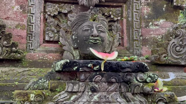 Stone relief of Bhoma with offerings and burning incense placed among carved decorative elements in a traditional religious setting. Sacred tradition.