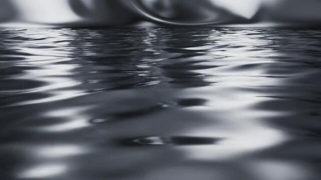 Reflective liquid surface with soft light creating ripples and waves in a dark grey and silver metallic tone Keywords: liquid, metal, fluid, abstract, surface, waves, reflection, shiny, metallic