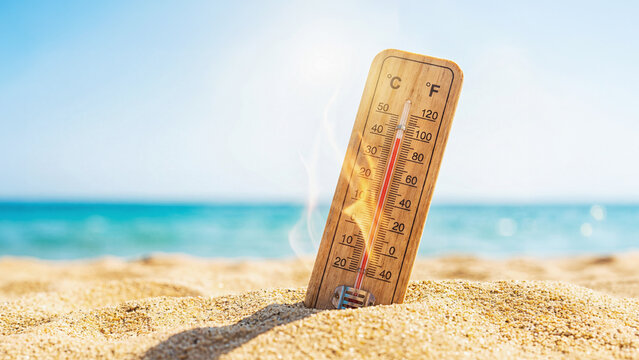 Beach on a hot summer day with sun and a thermometer. Extremely hot weather forecast.