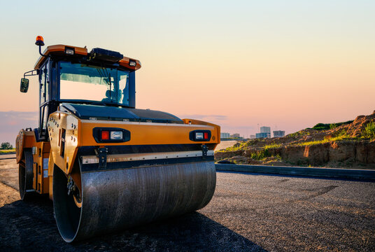 Road roller on asphalt road construction. Vibrator compactor machine on roadworks, asphalt pavement. Asphalt paving installation. Vibration roller on highway asphalting. Road compaction equipment. 