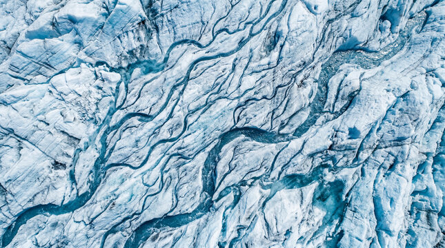 Macro abstract photo of flowing meltwater lines carving small unique channels through glacier ice surface
