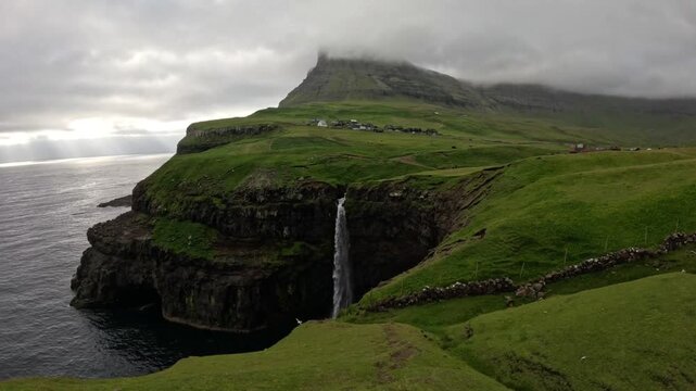 Majestic M&uacute;lafossur waterfall dropping into the ocean, Faroe Islands